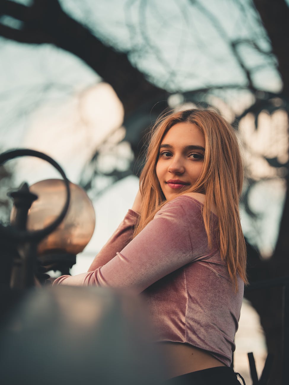 Portrait of a smiling woman outdoors with a warm, natural background and a soft pastel look.